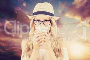 Composite image of gorgeous blonde hipster drinking out of take-