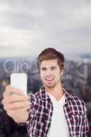 Composite image of happy hipster taking selfie