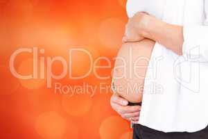 Composite image of midsection of pregnant woman holding belly