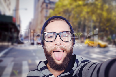 Composite image of portrait of happy hipster sticking out tongue