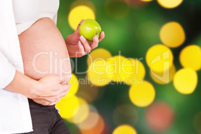 Composite image of midsection of pregnant woman holding green ap