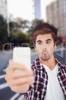 Composite image of man making face while taking selfie