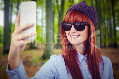Composite image of smiling hipster woman taking selfie