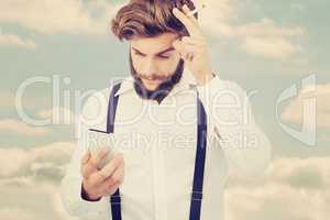 Composite image of hipster looking in mobile phonewhile holding