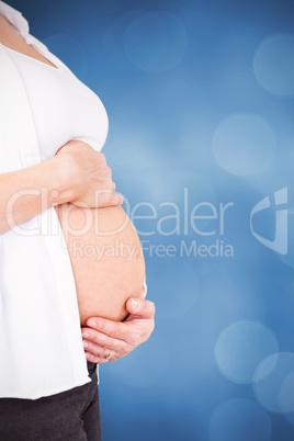Composite image of side view of pregnant woman holding stomach