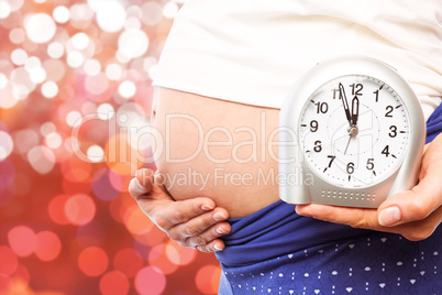 Composite image of pregnant woman showing clock and bump