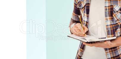 Composite image of mid section of hipster writing with pencil on