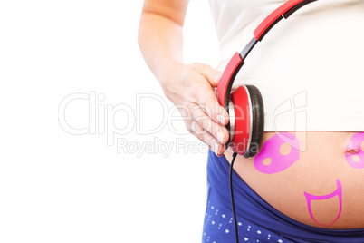 Composite image of pregnant woman holding earphones over bump