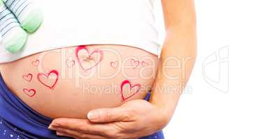 Composite image of pregnant woman holding baby shoes over bump