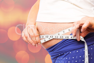 Composite image of pregnant woman measuring her bump