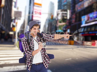 Composite image of happy man pointing while holding camera