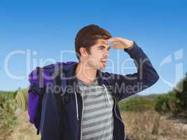 Composite image of man with backpack shielding eyes