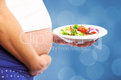 Composite image of pregnant woman eating a salad