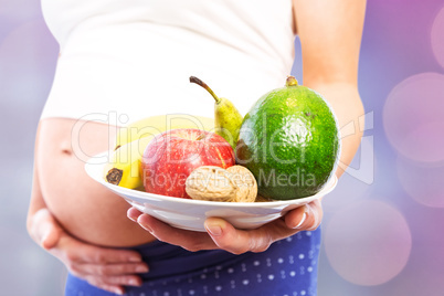Composite image of pregnant woman showing fruit and veg