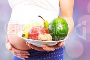 Composite image of pregnant woman showing fruit and veg