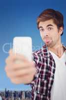 Composite image of hipster making face while taking selfie
