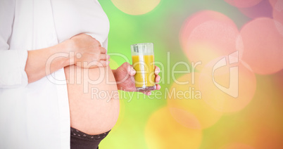 Composite image of midsection of pregnant woman holding glass of