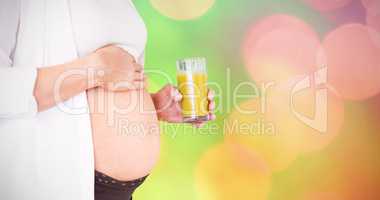 Composite image of midsection of pregnant woman holding glass of