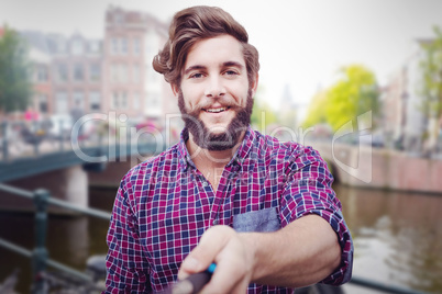 Composite image of portrait of hipster using selfie stick
