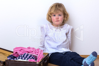 Little girl with clothes suitcase