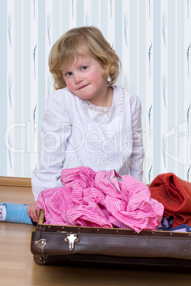 Little girl with clothes suitcase