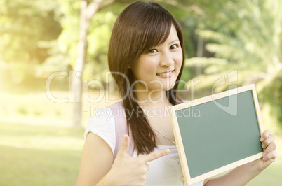 Asian college student pointing at blank chalkboard