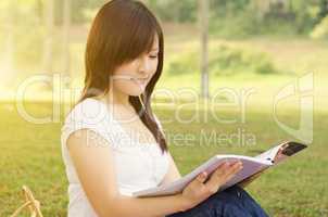 Young Asian college girl student reading book