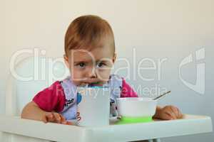 small child drinks water sitting on the highchair
