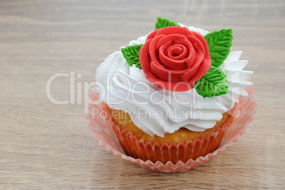 Muffin with cream decorated with sugar rose