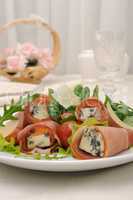 Rolls of jamon with blue cheese in lettuce leaves and parmesan