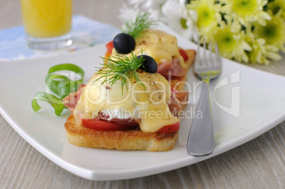 Eggs Benedict with ham and tomato on toast with cheese