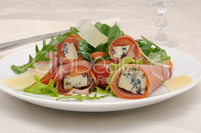 Rolls of jamon with blue cheese in lettuce leaves and parmesan