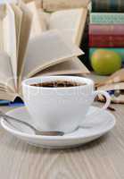 A cup of coffee on a table among books