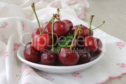 plate of ripe cherries on the table with a napkin