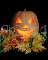 Glowing carved pumpkin in autumn leaves