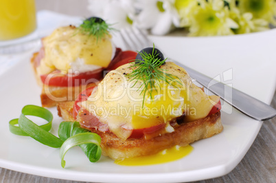 Eggs Benedict with ham and tomato on toast with cheese