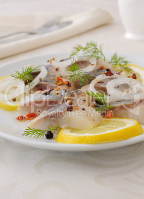 Slices of salted herring with onion, lemon and spices