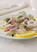 Slices of salted herring with onion, lemon and spices