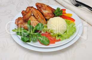 Baked chicken wings with garlic and potatoes and vegetables