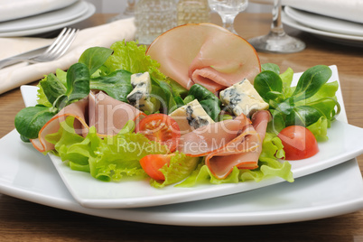 Appetizer with slices of jamon and blue cheese with cherry