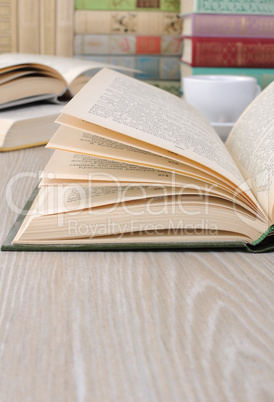 Open book on a table among other books