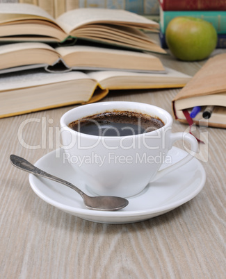 A cup of coffee on a table among books