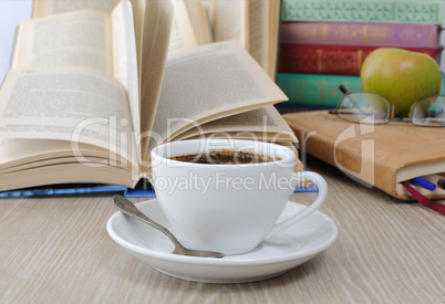 A cup of coffee on the table against the background of an open b