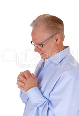 Praying senior man with folded hands.