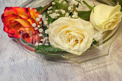 The roses on the table on a glass dish.
