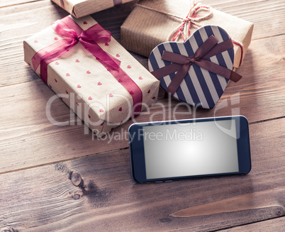 Smart phone near gift boxes. Clipping path included.