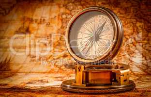 Vintage compass lies on an ancient world map.