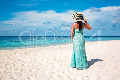 Girl walking along a tropical beach in the Maldives.