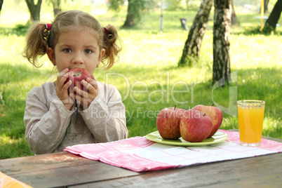 little girl eat apple in park