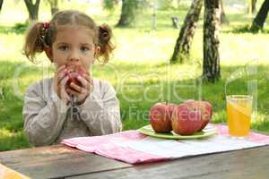 little girl eat apple in park